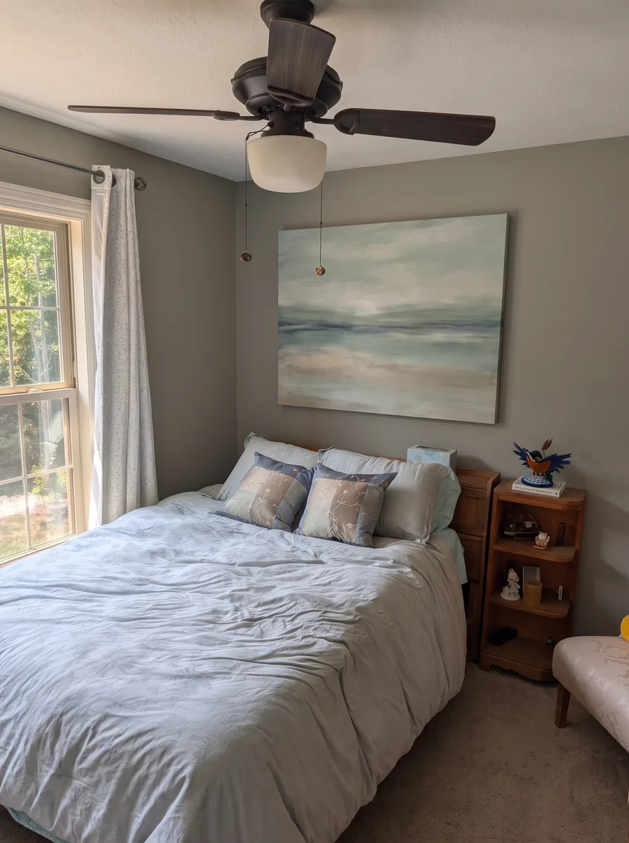 A calm bright bedroom with a wide canvas of soft coastal abstract art above the bed